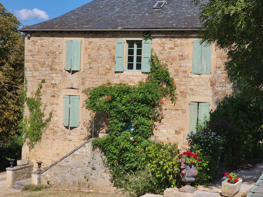 Façade d'une maison en pierre aux volets verts